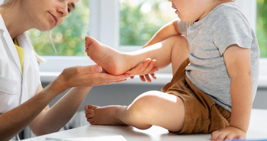 orthopedist podiatrist checking child patient feet condition in clinic office