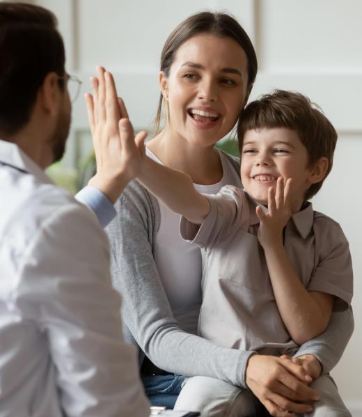 Happy cute little boy giving high five to pediatrician, friendly doctor greeting preschool patient at medical appointment, good checkup result, young mum and son visiting gp in hospital